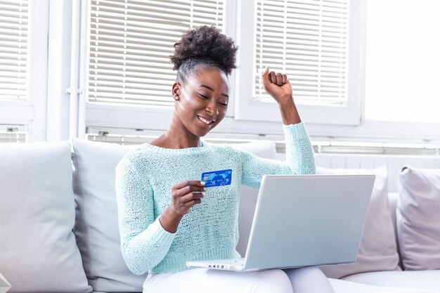 Frau, die Kreditkarte hält und einen Laptop benutzt