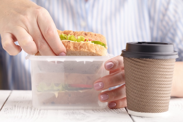 Frau, die Lachspaninisandwich mit Tomaten und Käse bei der Arbeit isst