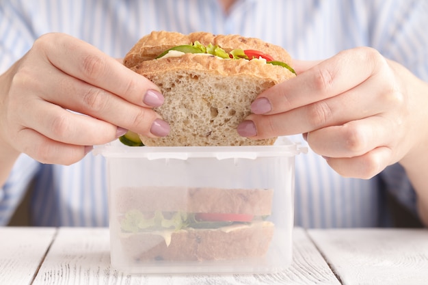 Frau, die Lachspaninisandwich mit Tomaten und Käse bei der Arbeit isst