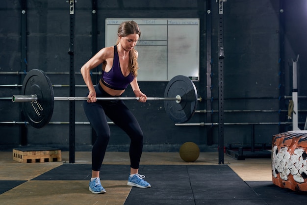 Frau, die Langhantel im Fitnessstudio hebt