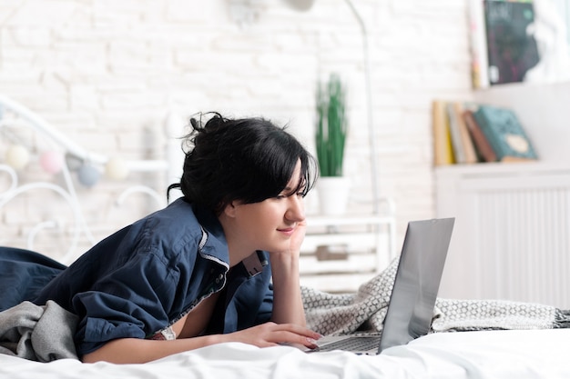 Frau, die Laptop auf Bett googelt