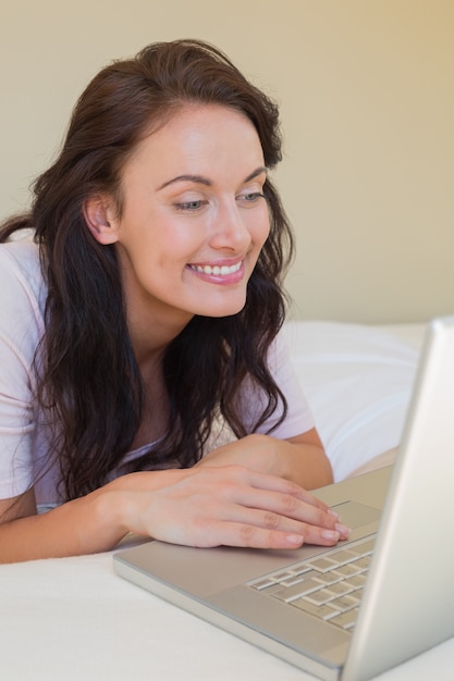 Frau, die Laptop im Bett verwendet