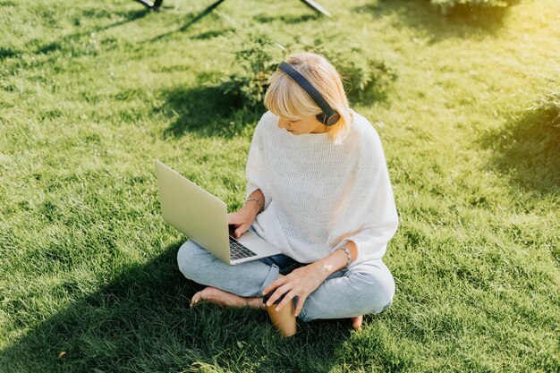 Frau, die Laptop sitzt auf dem Gras