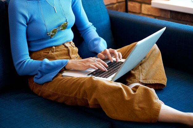 Frau, die Laptop zu Hause sitzt auf Sofa