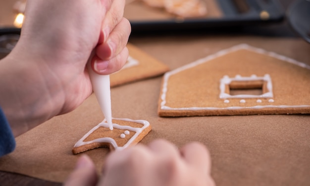 Frau, die Lebkuchenhaus mit Zuckergussglasur-Belag verziert