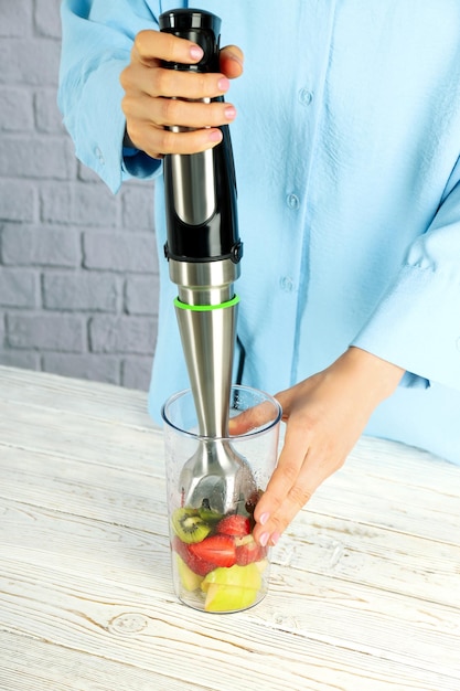 Foto frau, die leckeres gesundes essen mit mixer kocht