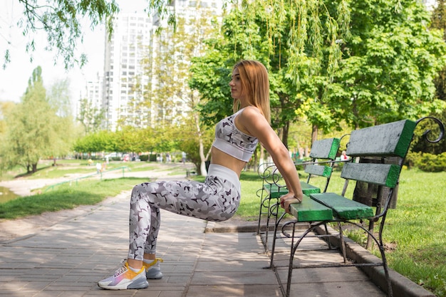 Foto frau, die liegestütze nahe einer bank im park tut