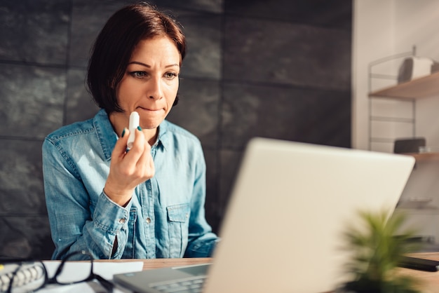 Frau, die Lippenbalsam bei der Arbeit anwendet