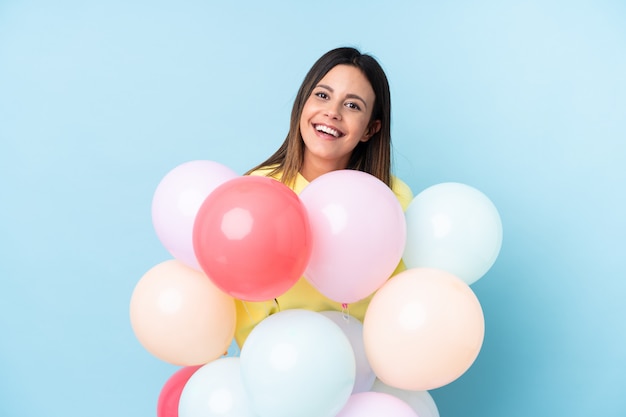 Frau, die Luftballons in einer Partei über blauer Wand hält