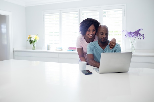 Frau, die Mann beim Verwenden des Laptops umarmt