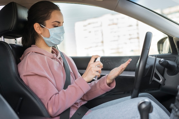 Foto frau, die maske trägt und händedesinfektionsmittel verwendet