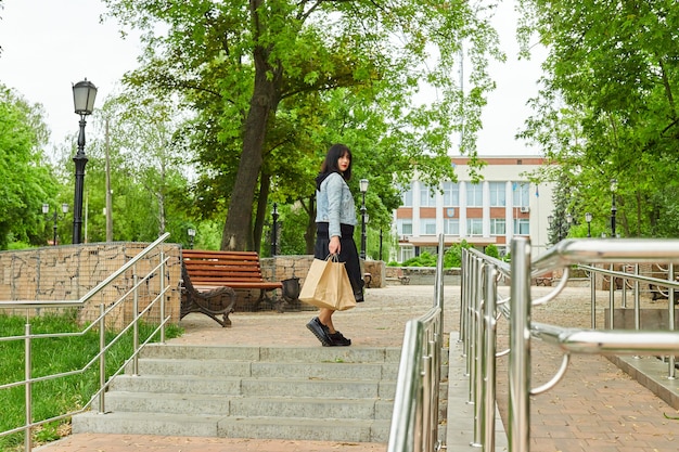 Frau, die mehrere Papiertüten hält, die draußen im Park spazieren gehen