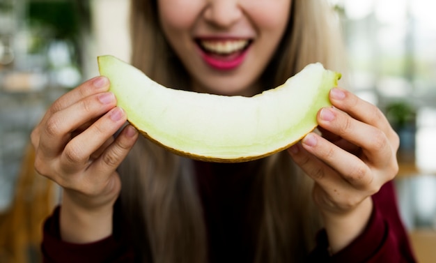 Frau, die Melonenhonigtau mit Lächeln isst