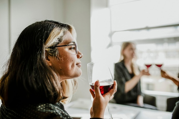 Frau, die mit Freunden ein Glas Rotwein trinkt