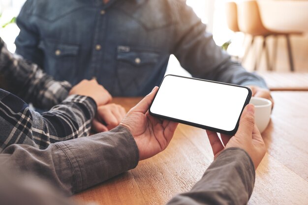 Frau, die mit Freunden im Büro ein Mockup-Handy benutzt und betrachtet