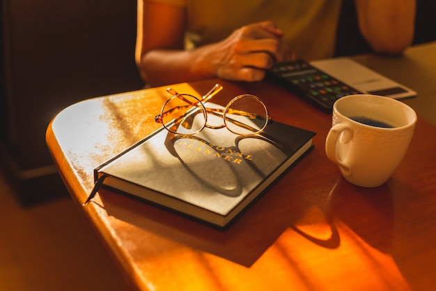 Frau, die mit Handy mit Kaffeetasse auf Tisch arbeitet.