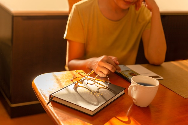 Frau, die mit Handy mit Kaffeetasse auf Tisch arbeitet.