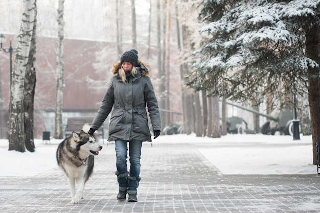 Frau, die mit heiserem Hund im Winter geht.