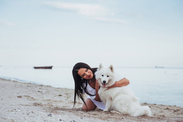 Frau, die mit ihrem Hund am Strand spielt