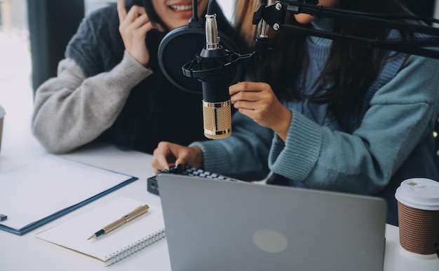 Frau, die mit Kopfhörern und Mikroskop einen Podcast auf ihrem Laptop aufnimmt, weibliche Podcaster, die einen Audio-Podcast aus ihrem Heimstudio macht