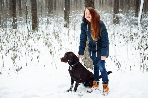 Frau, die mit Labrador-Hund im Wald geht