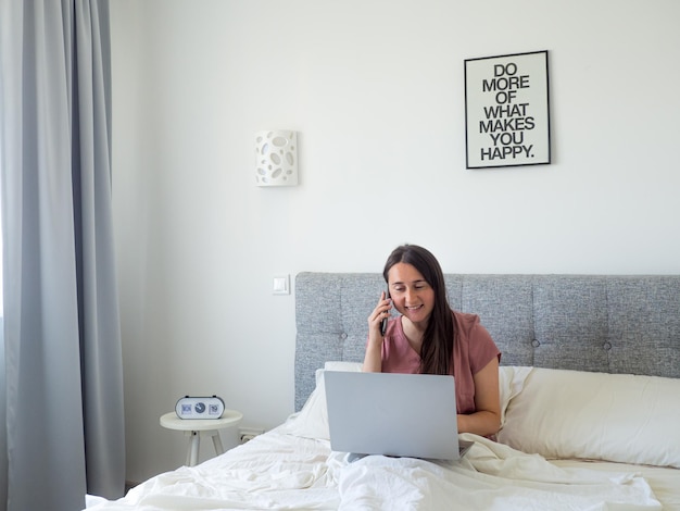 Frau, die mit Laptop auf dem Bett arbeitet