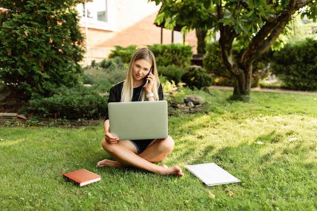 Frau, die mit Laptop draußen im Park lernt