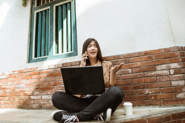 Frau, die mit Laptop und ihrem Handy arbeitet