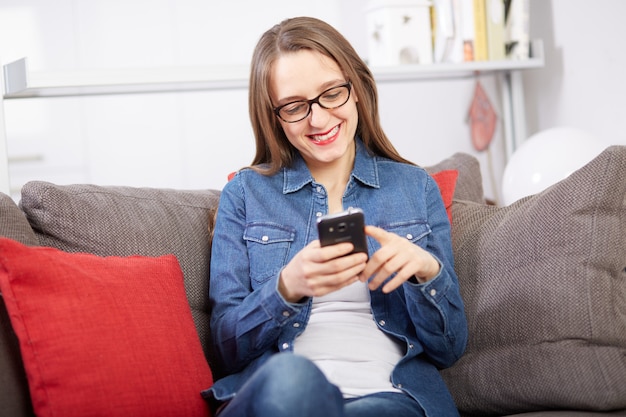 Frau, die mit Mobile auf Sofa spricht