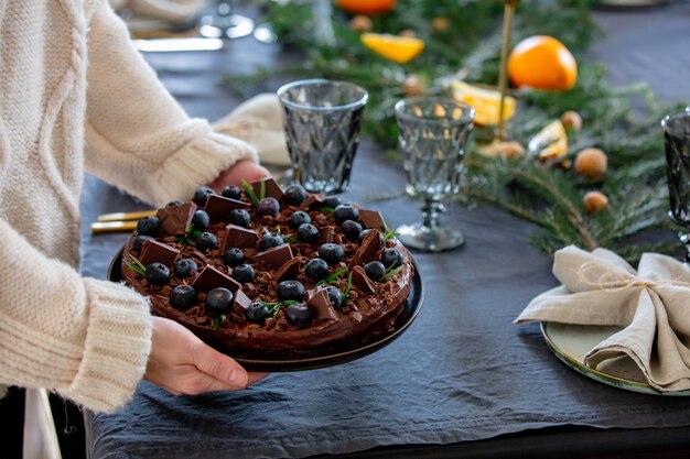 Frau, die mit Sahne Schokoladenkuchen über einer Tabelle hält