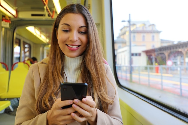 Frau, die mit Smartphone auf Straßenbahn sitzt