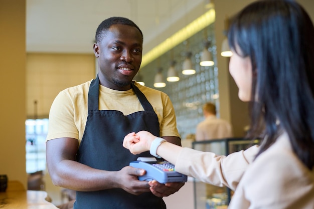 Frau, die mit Smartwatch im Café bezahlt