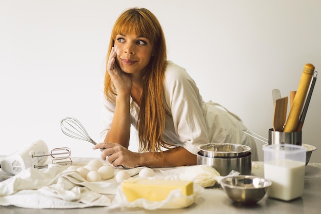 Frau, die mit Teigvorbereitungsrezeptbrotpizza oder -kuchen arbeitet, die Zutaten kochen, die Kuchen kochen