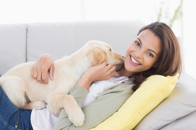 Frau, die mit Welpen auf Sofa spielt