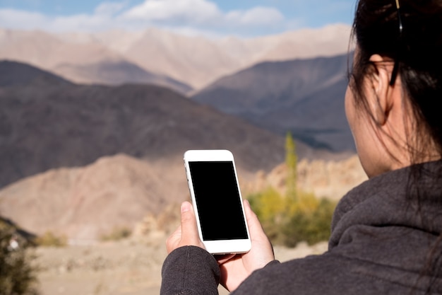 Frau, die Modelltelefon mit Berg hält