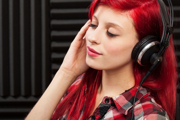 Frau, die Musik mit Kopfhörern in einem Berufsstudio hört