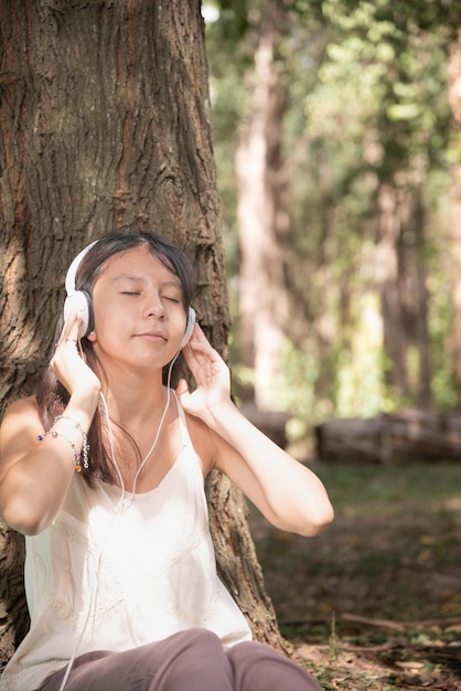 Frau, die Musik mit Kopfhörern und Notizbuch hört