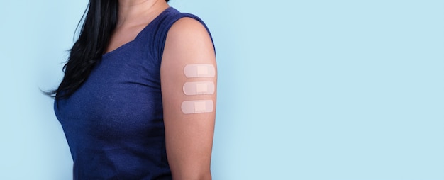 Frau, die nach Coronavirus-Impfstoff viele Pflaster auf der Schulter zeigt, neues Briefmarkenkonzept, Mutation Covid-19, Panorama-Layout