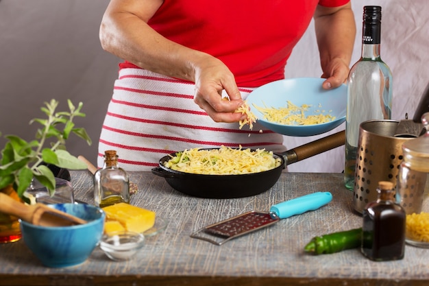 Frau, die Nudeln mit weißer Sahnesauce zu Hause in der Küche kocht