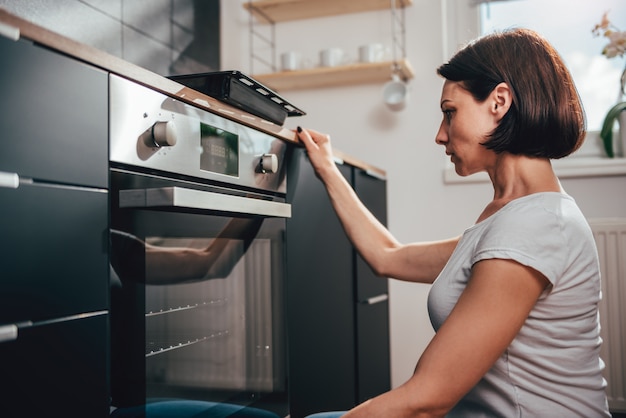 Foto frau, die ofen verwendet