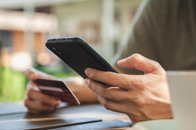 Foto frau, die online mit kreditkarte im café im freien einkauftnahaufnahme der hand mit smartphone