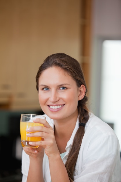 Frau, die Orangensaft beim Lächeln trinkt