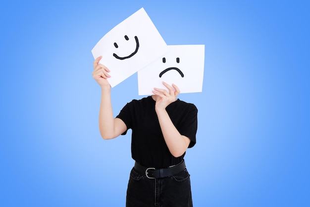 Foto frau, die papier mit smiley und traurigem gesicht auf ihrem gesicht hält. sofortige psychologische veränderung