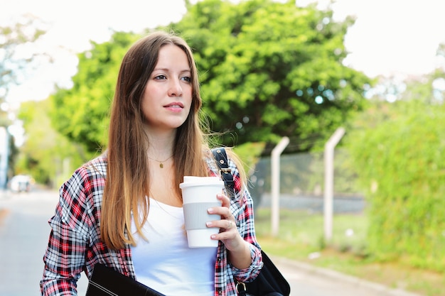 Frau, die Papierkaffeetasse in der Straße hält.