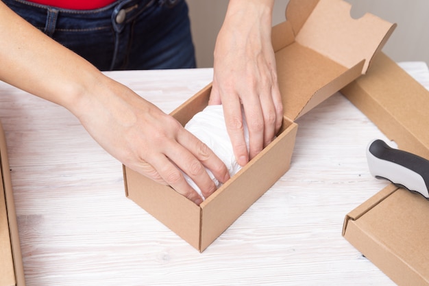 Foto frau, die pappkartons verpackt, produkte pflückt und puttind