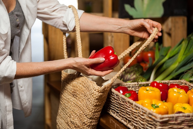 Frau, die Paprika am organischen Abschnitt kauft