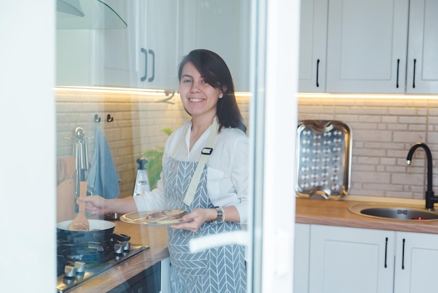 Frau, die Pfannkuchen kocht, Blick durch das Fenster