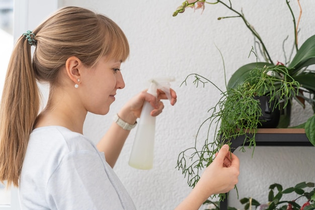 Frau, die Pflanzen und Blumen mit Plastikflasche auf Balkon gießt. Botanisches Hobby