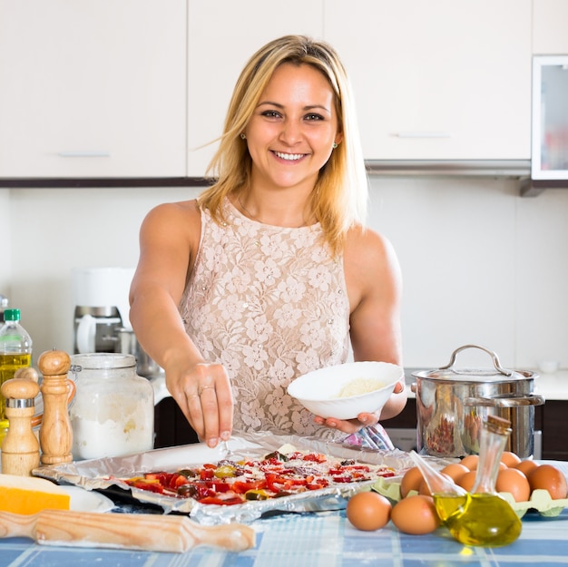 Frau, die Pizza mit Salami kocht