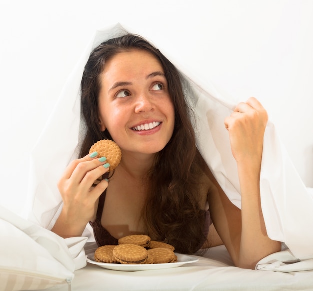 Frau, die Plätzchen im Bett isst